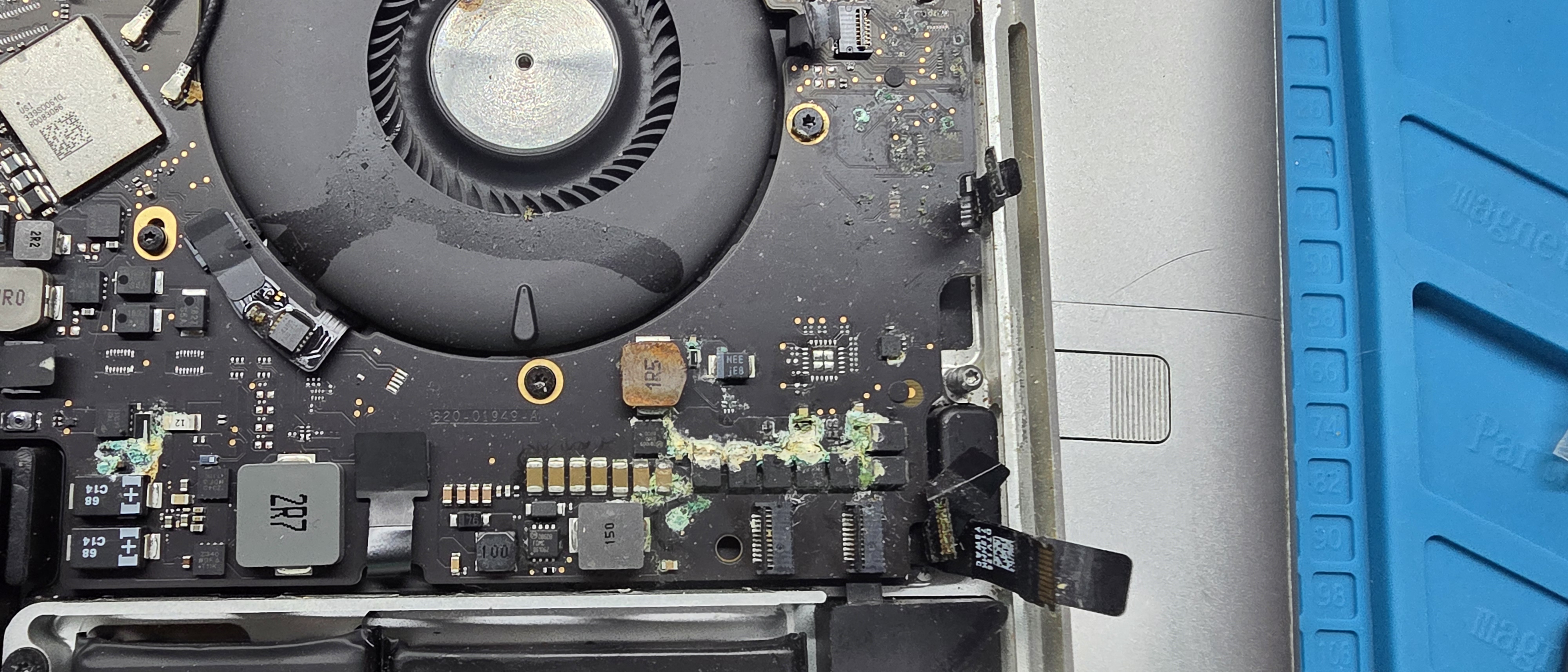 Close-up of liquid corrosion on a MacBook Pro logic board near the fan