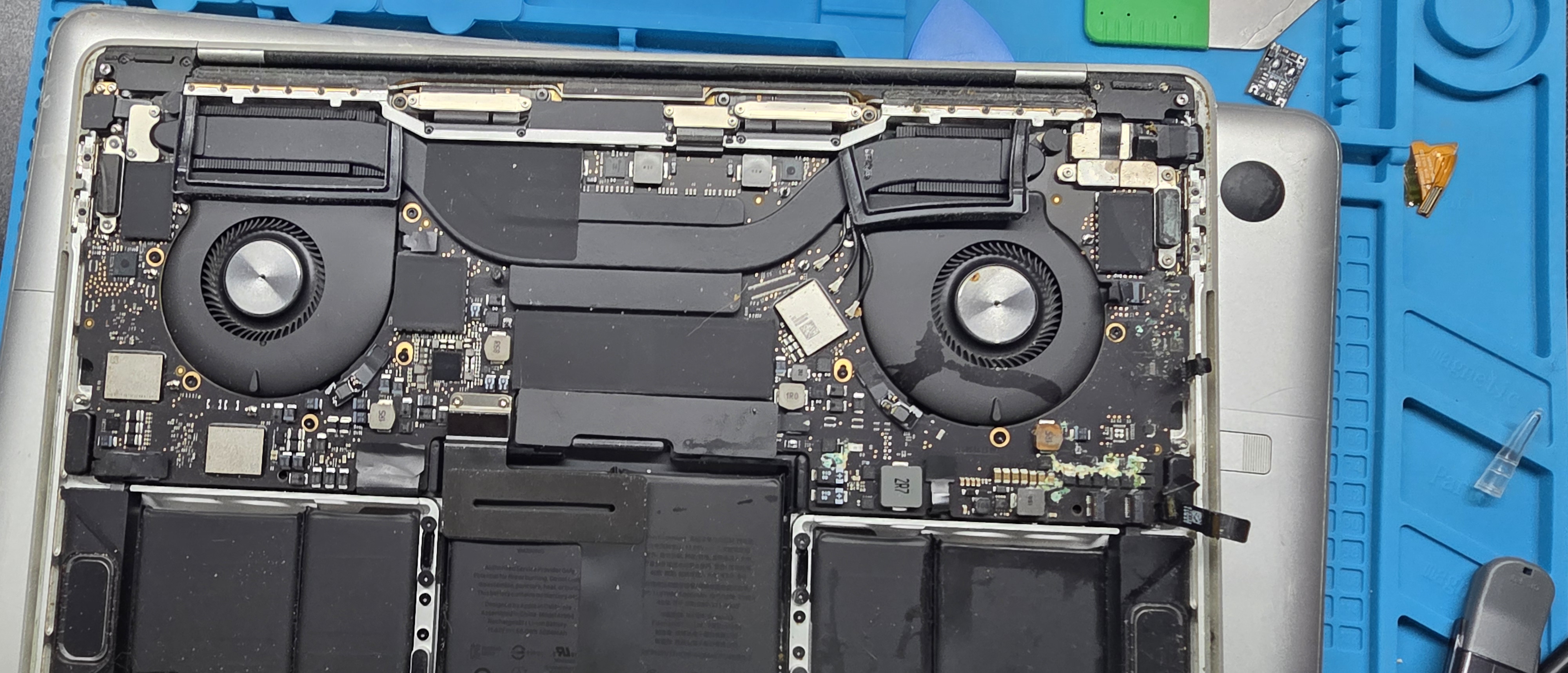 Open MacBook Pro on the Circuit Savages Palmdale bench after a liquid spill