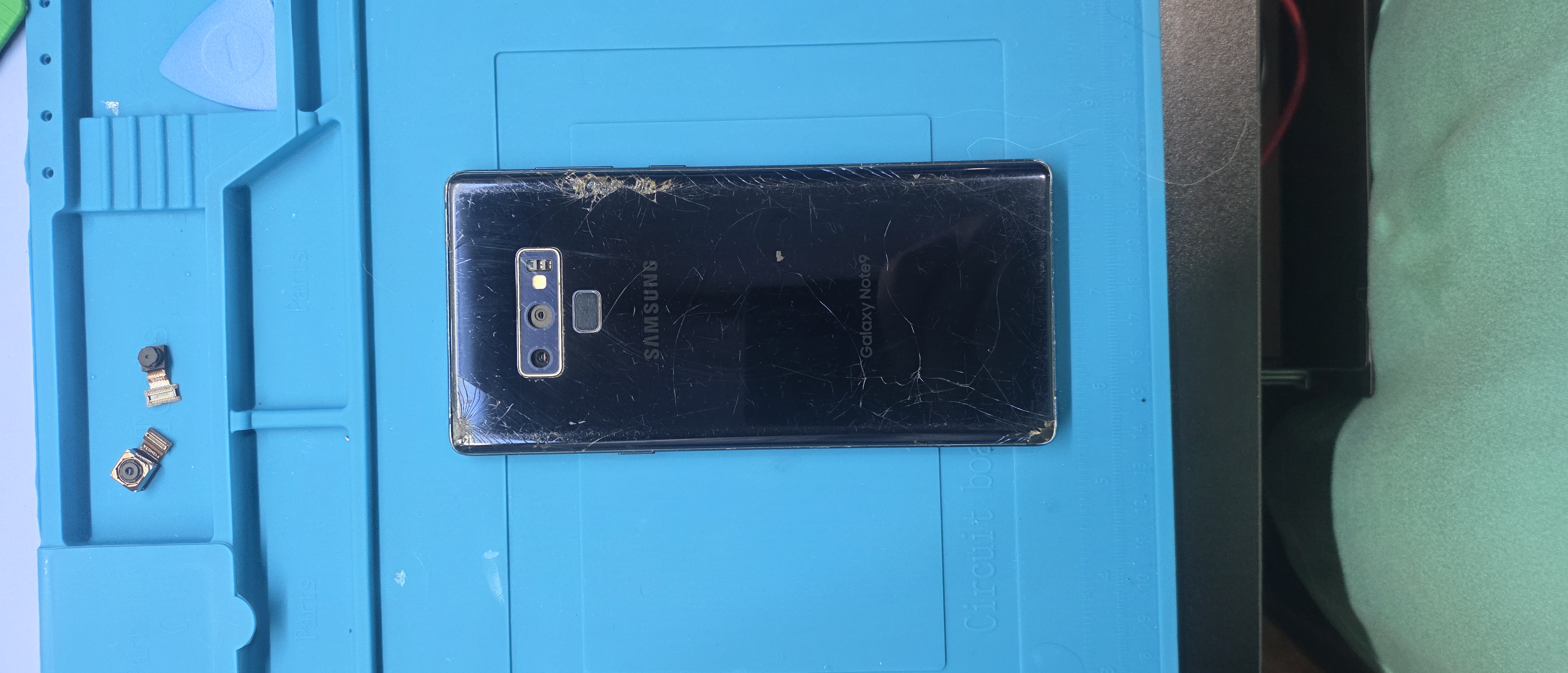 Samsung Galaxy Note 9 with cracked rear glass on the Circuit Savages mat